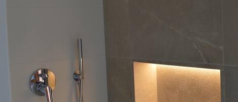 A modern bathroom with a showerhead, handheld shower, and a built-in bathtub.