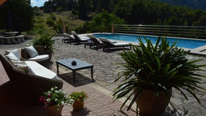 A pool area with lounge chairs, a table, and potted plants.