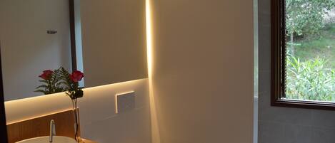A modern bathroom with a wooden vanity, a white sink, and a large mirror.
