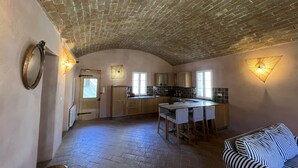 A spacious kitchen with a brick ceiling, wooden cabinets, and a dining area with striped chairs. - Pigna: Charming village house, 5 km from the sea, vaulted and whitewashed (Pigna)
