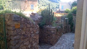A narrow stone pathway flanked by stone walls, leading to a building with a sign that reads "O Clario". - Pigna: Charming village house, 5 km from the sea, vaulted and whitewashed (Pigna)