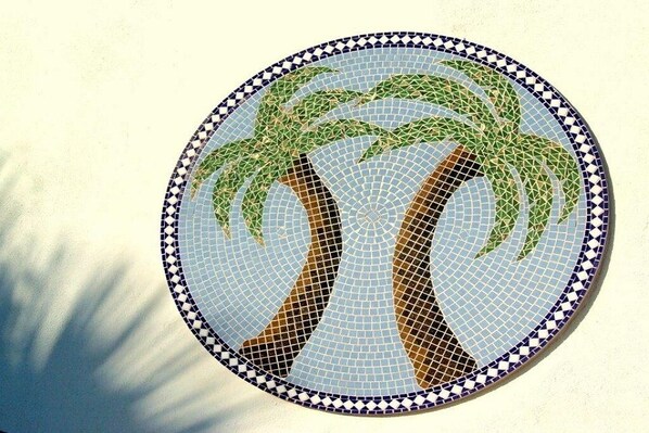 A circular mosaic tile with a palm tree design.