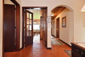 A hallway with wooden doors, a tiled floor, and a view into a room with a sofa and chairs. - Casa do Moinho, villa with a heated pool near the beach in Sintra, self check-in (Ulgueira-Colares)