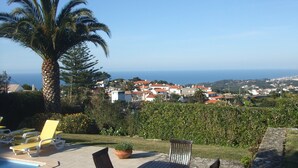 Un patio con piscina, mobiliario exterior y vista a un pueblo costero.