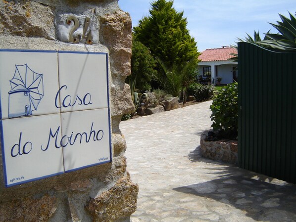 A stone pathway leading to a building with a sign reading "Casa do Moinho".