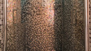 Una ducha con paredes de azulejos decorativos y puerta de cristal.
