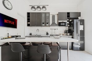 A modern kitchen with a central island, bar stools, a refrigerator, and a microwave. - Luxury 3 bedroom apartment 4 bathrooms living room and kitchen. (Roma)