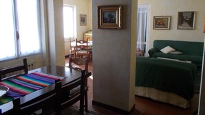 A room with a bed, a table with chairs, and a window.