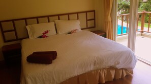 Relax in this inviting room with a large bed, nightstands, and a sliding door leading to a pool view.