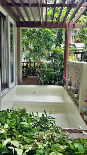 Relax in a serene outdoor space surrounded by lush greenery and a wooden pergola.