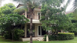 Set amidst lush greenery, this two-story residence offers a peaceful retreat with a balcony and garden surroundings.