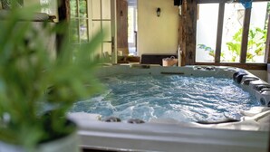 Banheira de hidromassagem com água, interior de madeira e uma janela com plantas lá fora.