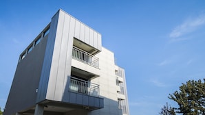 A modern building with a flat facade, multiple balconies, and a clear sky. - W Ocean Pension (Seogwipo)