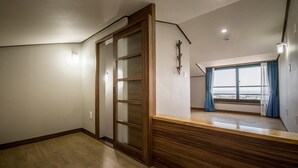 A room with a sliding door, a wooden counter, and a large window with curtains. - W Ocean Pension (Seogwipo)