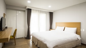 A hotel room with a bed, a desk, a chair, and a television. - W Ocean Pension (Seogwipo)