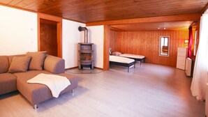 A cozy room with a wooden ceiling, a sofa, a bed, and a fireplace. - California House Klosters (Klosters-Serneus)