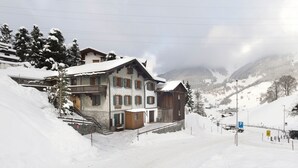 A snow-covered mountain village with traditional wooden houses, a ski lift, and a clear view of the surrounding mountains. - California House Klosters (Klosters-Serneus)