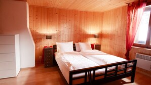 A wooden-paneled bedroom with a bed, nightstands, and a dresser. - California House Klosters (Klosters-Serneus)