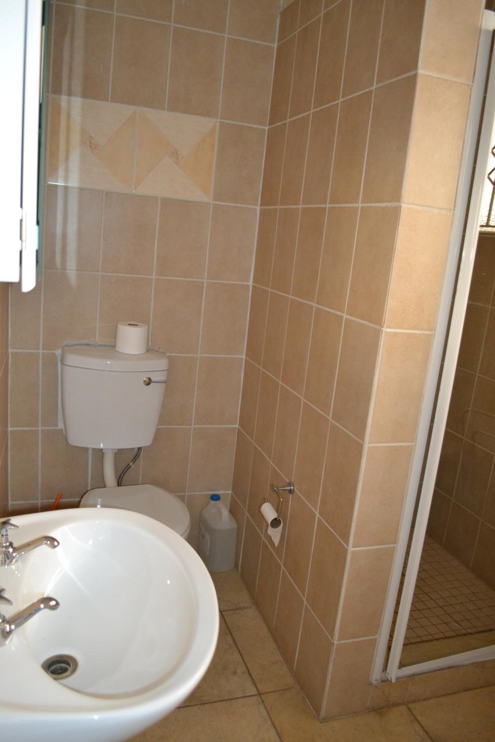 A bathroom with a toilet, sink, and shower area.
