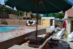 A pool area with lounge chairs, a hot tub, and a covered seating area. - Kamogelo Guest House (Moses Kotane)