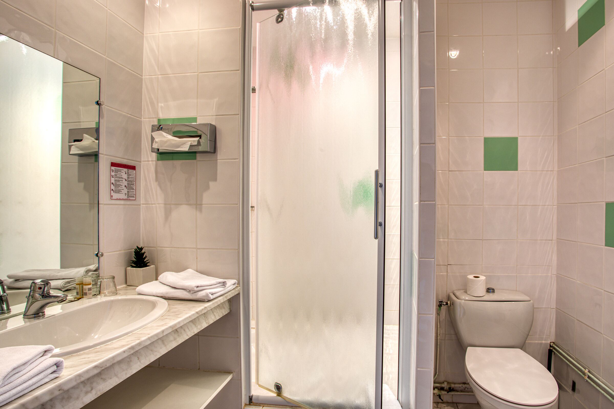 A bathroom with a glass-enclosed shower, a sink with a mirror, and a toilet.