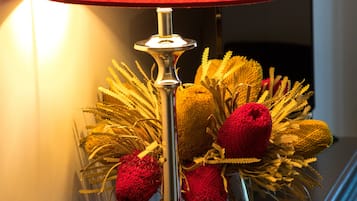 A lamp with a red shade and a vase with golden and red decorative elements on a table.