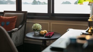 Una habitación con vista a un cuerpo de agua, una mesa con un florero y dos rollos de papel de cocina, además de una servilleta roja.