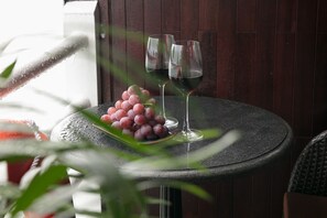 A table with two wine glasses and a bunch of grapes on a round table with a dark wooden background. - Halong Athena Cruise (Hon Gai)