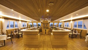 Un amplio espacio de bar con suelo de madera y una barra central, rodeado de mesas y sillas para comer.