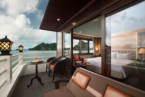 A balcony with a view of the sea, a table with drinks, and a sofa. - Halong Athena Cruise (Hon Gai)