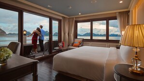 Habitación de hotel con una cama grande, un escritorio y vista al mar.