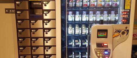 Un distributeur automatique proposant une variété de boissons, muni d’un compartiment pour les pièces et d’un lecteur de cartes.