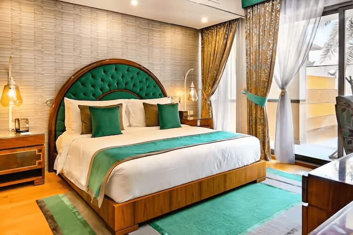 A neatly arranged bedroom with a large bed, wooden headboard, and green bedding.