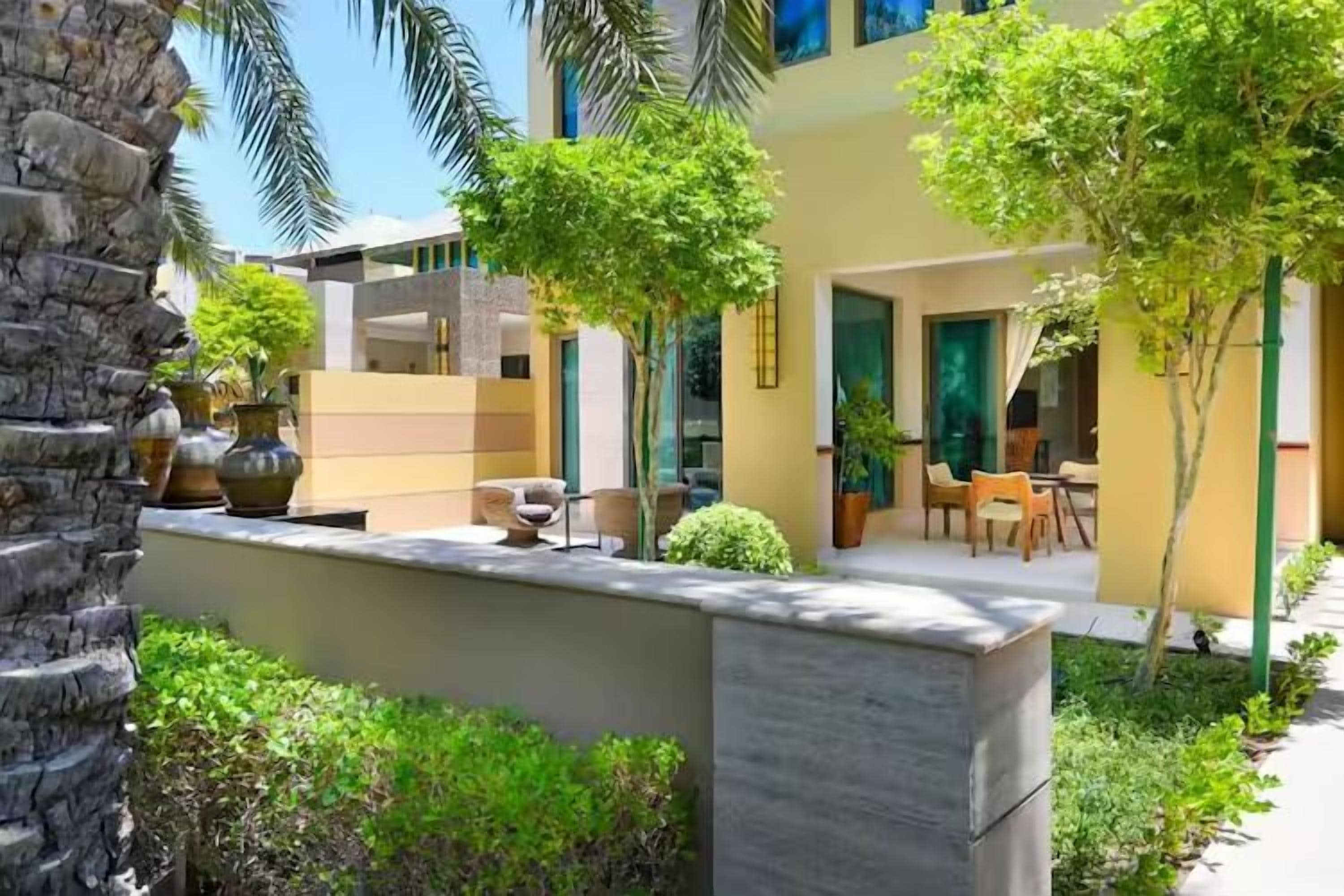 A modern outdoor area with a stone planter, seating, and a building with large windows and doors.