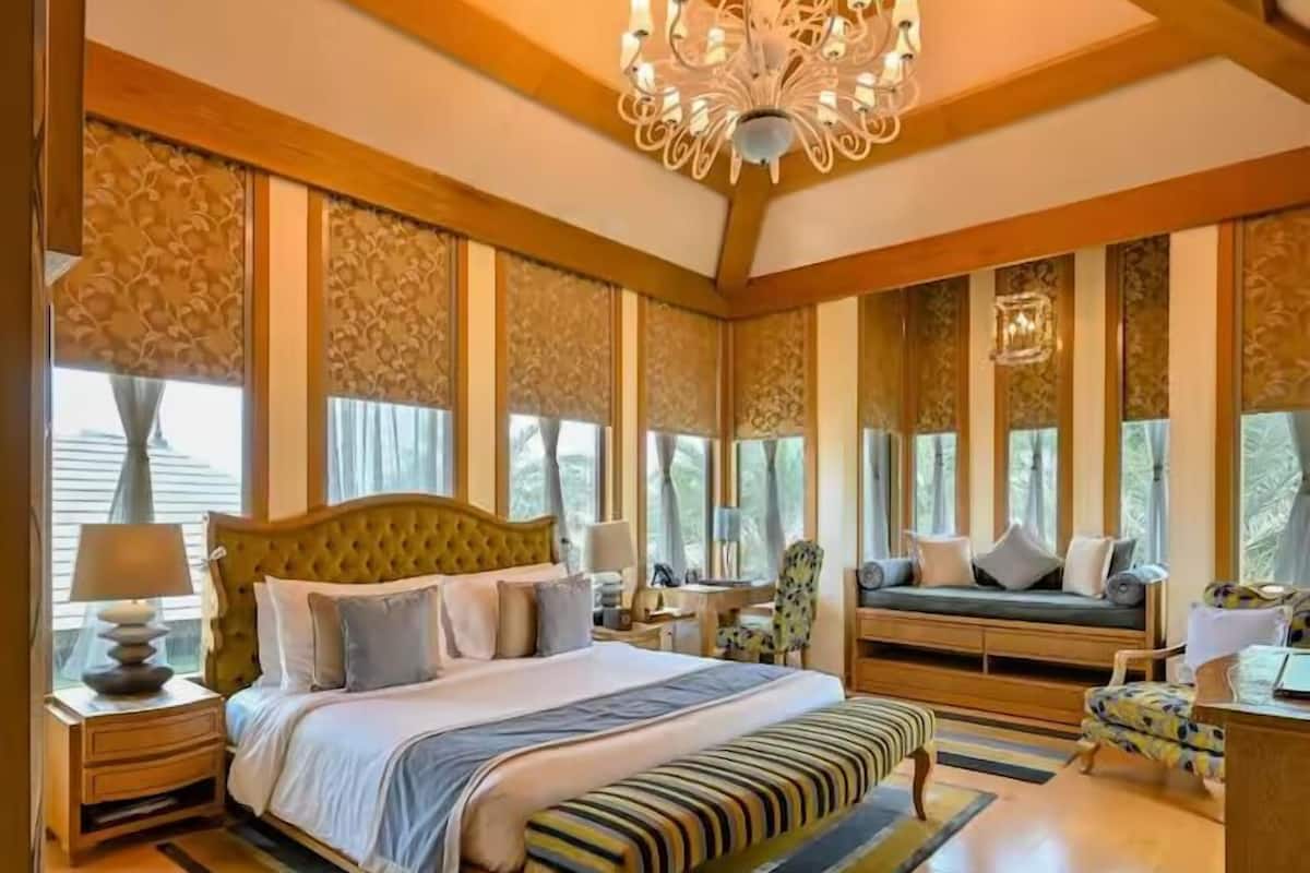 A spacious bedroom with a large bed, a bench, and a seating area with a view of the outdoors.
