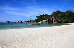 Ubicación cercana a la playa, arena blanca y sombrillas