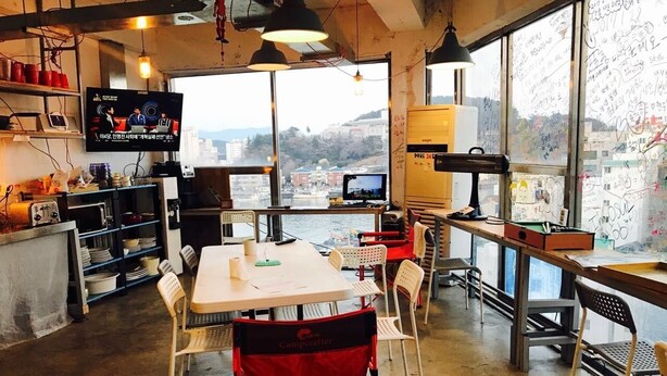A modern workspace with a large table, chairs, and a TV screen. - Life Guesthouse - Hostel (Tongyeong)