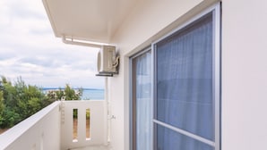 En balkon med havudsigt, et vindue med gardin og en airconditionenhed.