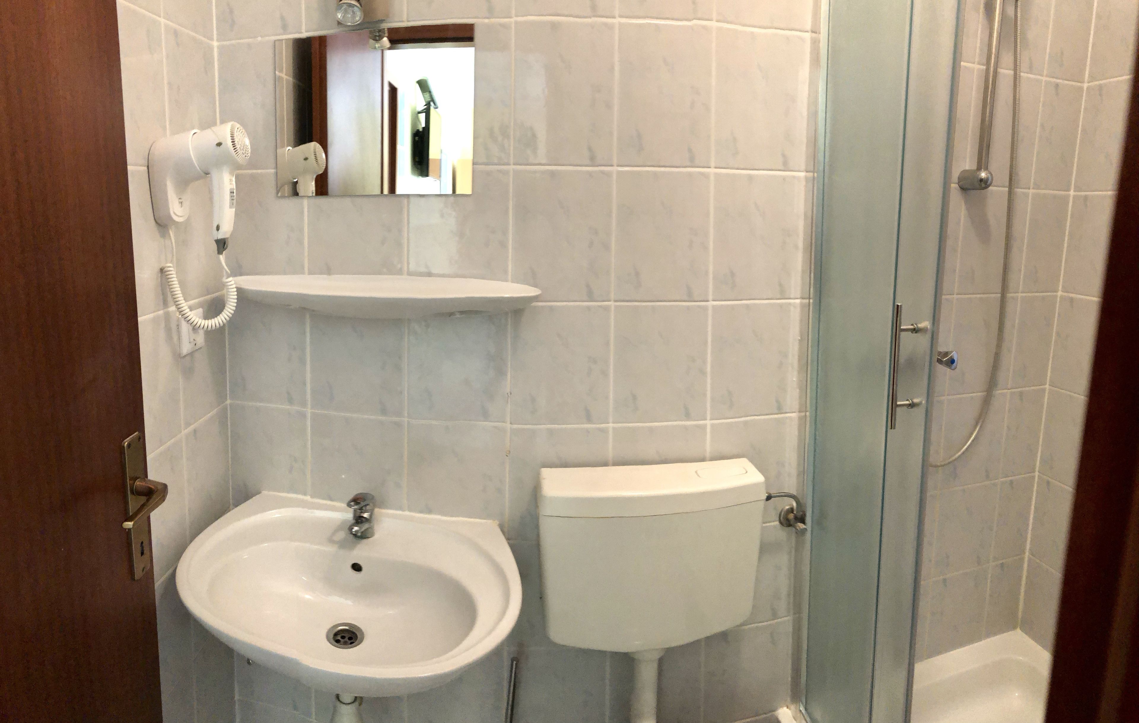 A bathroom with a sink, toilet, and a glass shower enclosure.
