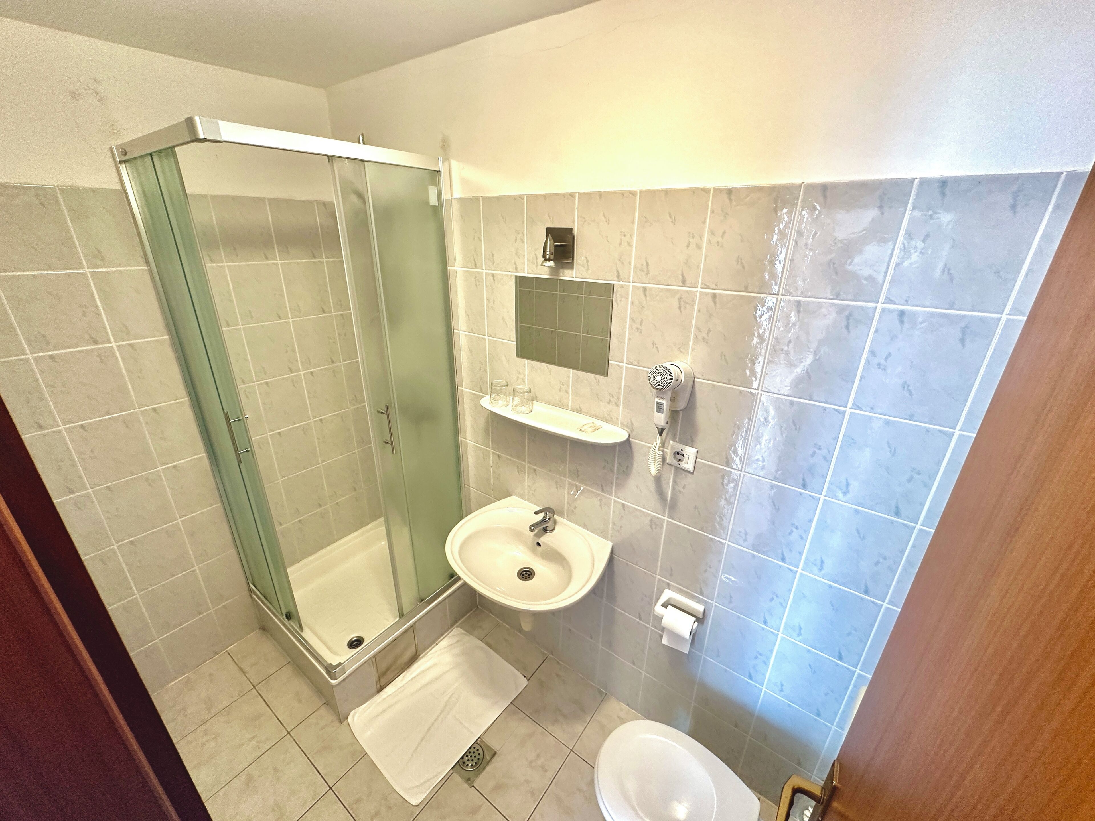Un baño con ducha de vidrio, lavamanos e inodoro.