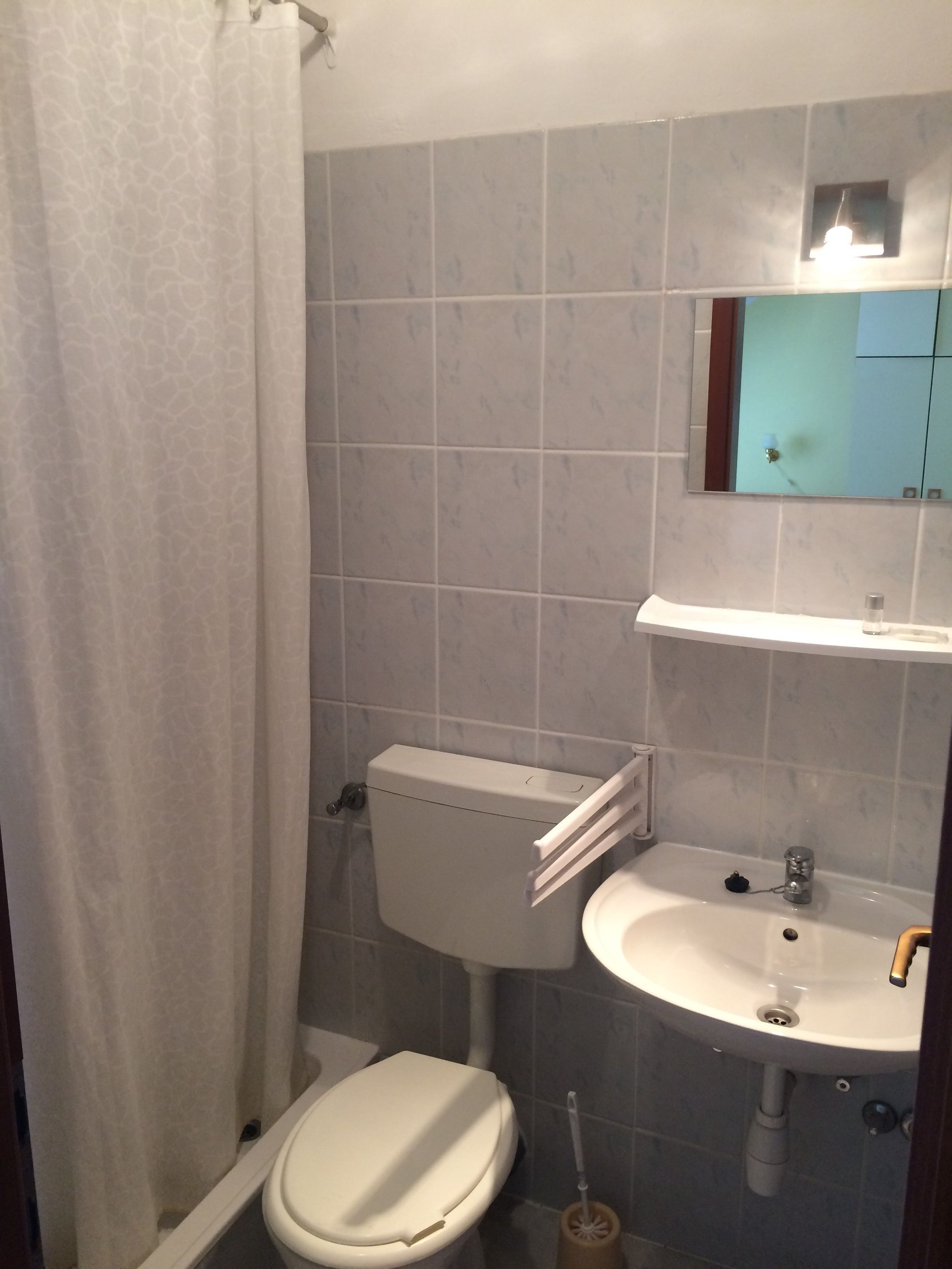 A small bathroom with a toilet, sink, and a mirror above the sink.