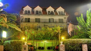 A multi-story residential building with a gated entrance, a covered driveway, and a well-maintained garden. - Pansion Begić (Dugi Rat)