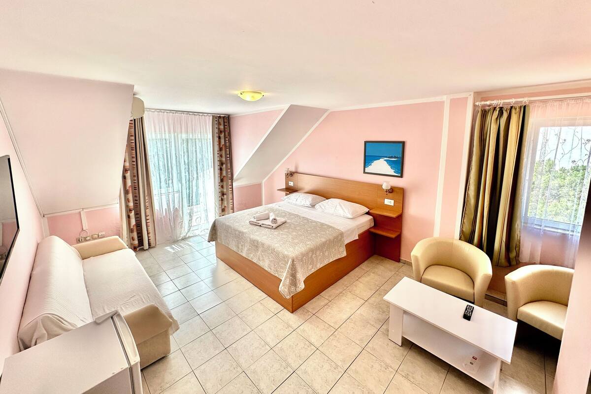 A hotel room with a bed, a desk, a chair, and a TV.