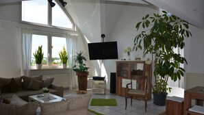 Een woonkamer met een bank, salontafel, televisie en potplanten.