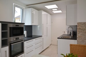 Resortwoning | Privékeuken | Een koelkast met diepvriezer, een microgolfoven, een oven, een kookplaat