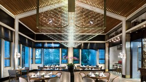 A spacious dining area with a central bar, large windows, and a chandelier. - Jinji Lake Grand Hotel (Suzhou)