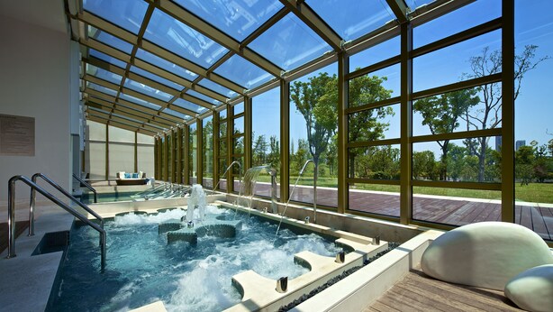 A glass-enclosed hot tub area with a view of a park and trees. - Jinji Lake Grand Hotel (Suzhou)