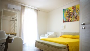 Hotellihuone, jossa on sänky, tuoli, työpöytä ja taulu seinällä.