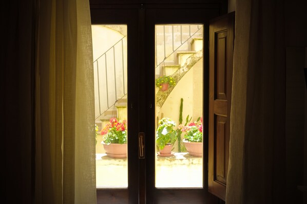 Una puerta que da a un patio con plantas en macetas y una escalera.