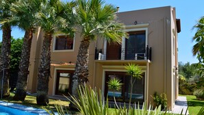 A two-story building with a pool, surrounded by palm trees and greenery. - Gold Luxury Villa Ialysos (Rhodes)